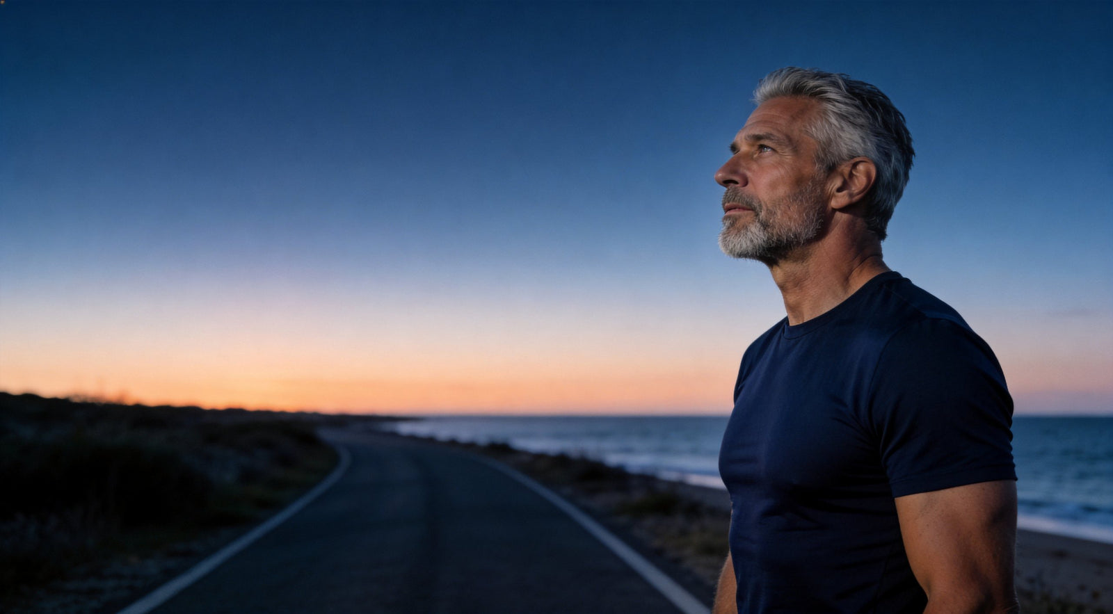 A man at dawn on a coastal road after a run